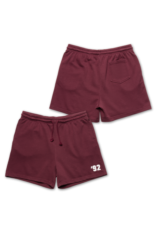 Two pairs of maroon shorts on a white background