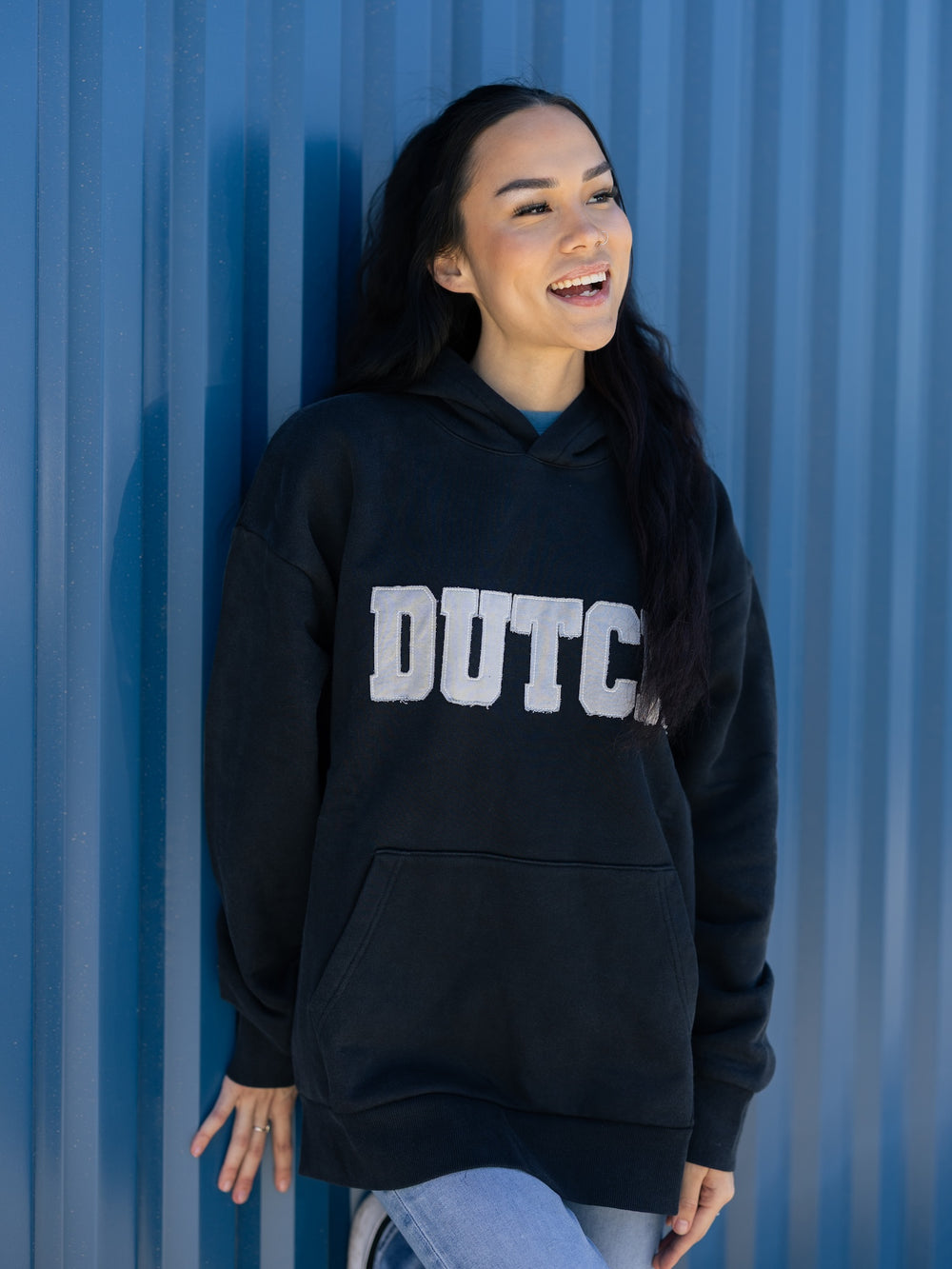 Person wearing a black hoodie with 'DUTCH' printed on it against a blue background