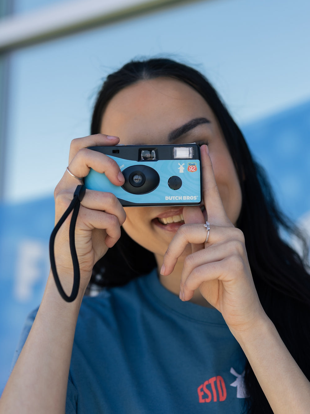Person holding a blue camera up to their face with a blurred background