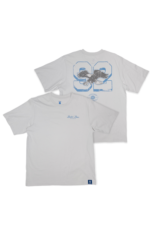Two light gray t-shirts shown against a white background, displaying the front and back views. The front shirt features a small blue script logo saying Dutch Bros on the left chest and on the back 92 with an eagle logo.