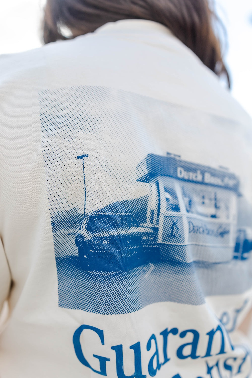 Close-up of a person wearing a jacket with a blue graphic and text on the back.